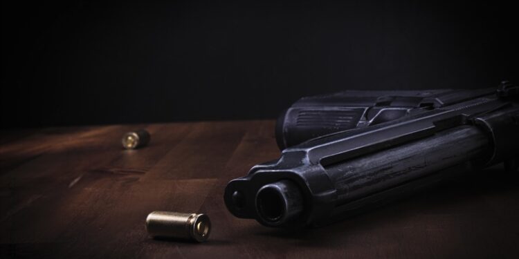 gun with a bullet on a wooden table