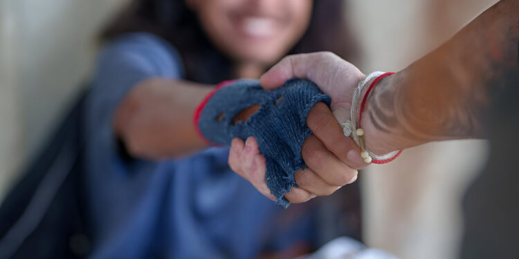 Close-up handshake homeless man on walkway street in the city., homeless poor people and depression concepts.