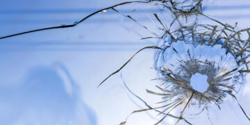 Dirty glass window with a bullet hole
