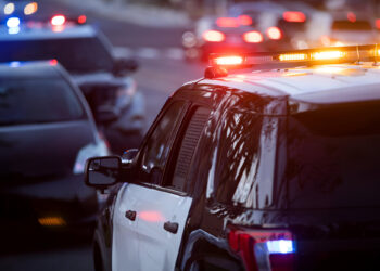 Police units pull over a car on a city street.