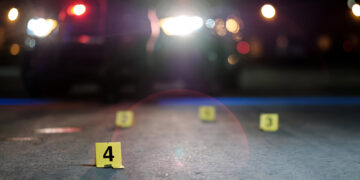 Shell casings are marked with evidence tags at a crime scene