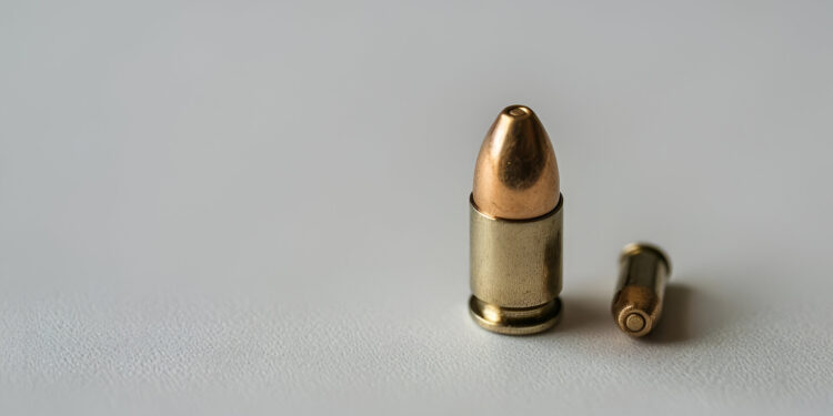 Single 9mm bullet on a blank white surface