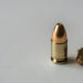 Single 9mm bullet on a blank white surface