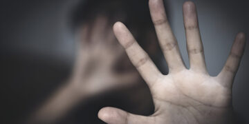 woman sit in a room with a hand signing meaning to stop