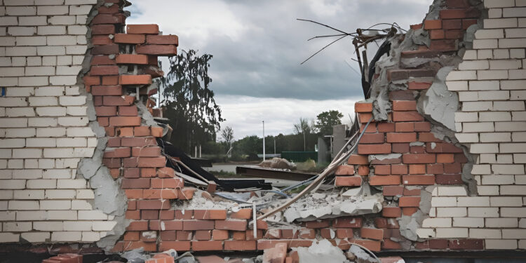 A destroyed brick wall cut out from a building with debris and broken bricks scattered around.
