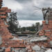 A destroyed brick wall cut out from a building with debris and broken bricks scattered around.