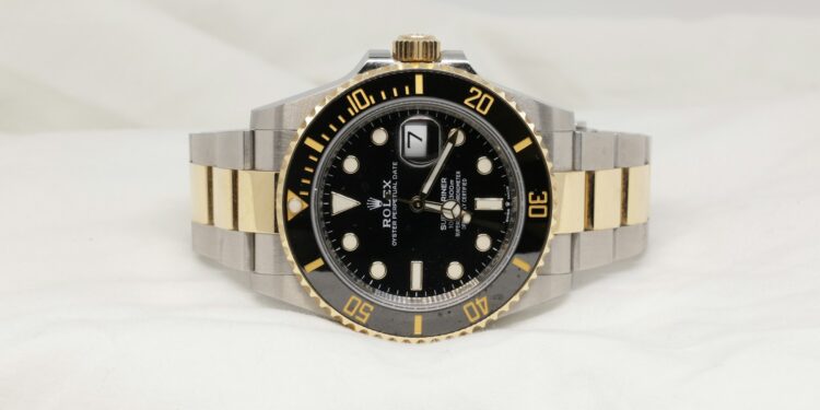 daniel-hay-O703kpzIsQI-unsplash-a black and gold rolex watch on a white background