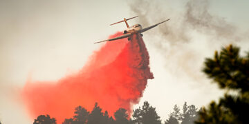 A large air tanker drops red fire retardant on wildfire