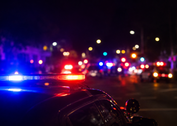 Blurred police lights at night following a deadly street takeover shooting in Carson.