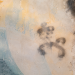 Close-up of a weathered mural wall with faded paint, light scorch marks and abstract spray-paint smudges, used as an illustrative image for a report on antisemitic vandalism at a Jewish temple site damaged by fire.