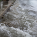 Close-up of floodwater rushing along a curb and wet sidewalk, used as an illustrative image for a Hollywood water main break that flooded nearby streets.