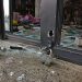 Close-up of a cut storefront lock, broken glass and scattered merchandise near an entrance.