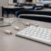 Close-up of a desktop computer keyboard and disconnected cables on an empty classroom desk.