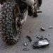 Close-up of a dirt bike rear tire and damaged side mirror debris on asphalt.