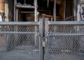 Close-up of a heavy metal security barrier secured in front of a damaged building entrance.