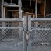 Close-up of a heavy metal security barrier secured in front of a damaged building entrance.