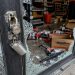 Close-up of a shattered auto parts store entrance with scattered boxes and broken lock hardware.