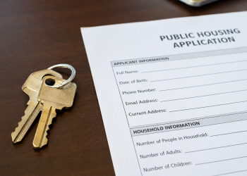 Close-up of apartment keys beside a public housing application form on a desk.