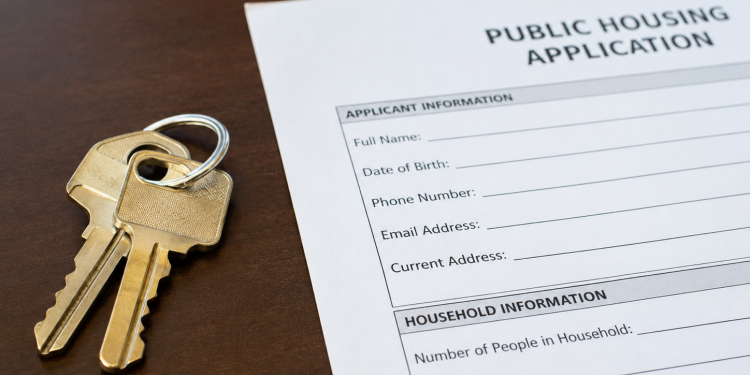 Close-up of apartment keys beside a public housing application form on a desk.