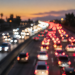 Close-up of blurred freeway headlights and taillights at dawn with traffic backed up in the distance.