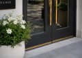 Close-up of freshly painted storefront doors, new planters and clean pavement outside a renovated shopping area.