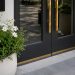 Close-up of freshly painted storefront doors, new planters and clean pavement outside a renovated shopping area.
