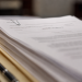 Close-up of legal documents labeled “indictment” resting on a manila folder beside a pen.