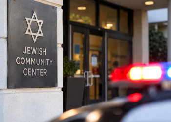 Close-up of a community center entrance with a blurred emergency light in the background, illustrating a reported threat against a Jewish community center.