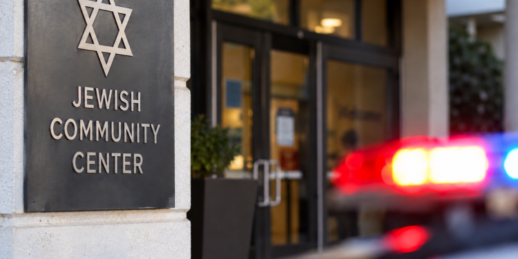 Close-up of a community center entrance with a blurred emergency light in the background, illustrating a reported threat against a Jewish community center.