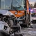 Close-up of a damaged SUV and Metro bus at a Southern California crash scene, with emergency vehicles and investigators blurred in the background.