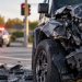Close-up of a damaged SUV at a suburban intersection, with blurred emergency lights in the background, illustrating a fatal high-speed crash investigation.