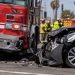 Close-up of a damaged firetruck and civilian vehicle at a South Los Angeles intersection, with traffic cones and blurred emergency responders in the background.