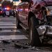 Close-up of a damaged pickup truck and roadway debris near a pedestrian crossing, with blurred emergency lights in the background, illustrating a hit-and-run investigation in Riverside.
