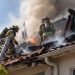Close-up of a fire-damaged apartment roof with firefighters working through heavy smoke, illustrating an apartment fire response in Beverly Hills.