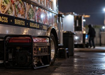 Close-up of a food truck at night with a portable generator and blurred surveillance-style background, illustrating an ongoing burglary investigation in Oxnard.