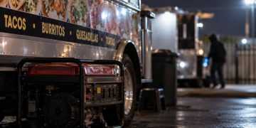 Close-up of a food truck at night with a portable generator and blurred surveillance-style background, illustrating an ongoing burglary investigation in Oxnard.