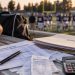 Close-up of a high school football field with a booster club finance folder, calculator and payment records in the foreground, illustrating an alleged embezzlement investigation.