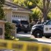 Close-up of a quiet Newbury Park residential street with a home entrance and blurred sheriff's vehicles in the background, illustrating a death investigation.