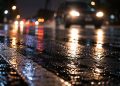 Close-up of a rain-covered roadway and blurred vehicle headlights at night, used as an illustrative image for a fatal hit-and-run crash in Laguna Beach.