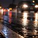 Close-up of a rain-covered roadway and blurred vehicle headlights at night, used as an illustrative image for a fatal hit-and-run crash in Laguna Beach.