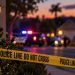Close-up of a suburban street at dusk with blurred emergency lights and police vehicles in the background, illustrating a fatal elder abuse investigation in Wildomar.
