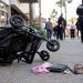 Close-up of a tipped stroller near a shopping center walkway, with blurred officers and pedestrians visible in the background.