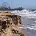 Close-up of an eroded Santa Monica beach with exposed sand layers and large waves, illustrating the coastal damage that forced Ocean Way Festival to be canceled.