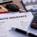Close-up of auto insurance documents and a calculator illustrating proposed California rate changes.