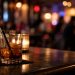 Close-up of cocktails on a bar counter with a heavily blurred nightlife background, illustrating the closure of a longtime West Hollywood bar and restaurant.