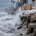 Close-up of storm waves striking an eroded Long Beach shoreline, with sandbags and coastal protection measures visible in the background.