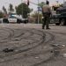 Close-up of tire marks and scattered debris across an intersection, with a blurred deputy and impounded vehicle visible in the background.