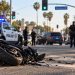 Daytime Studio City traffic collision scene with a damaged motorcycle in the foreground, police vehicles and officers blurred near the intersection.