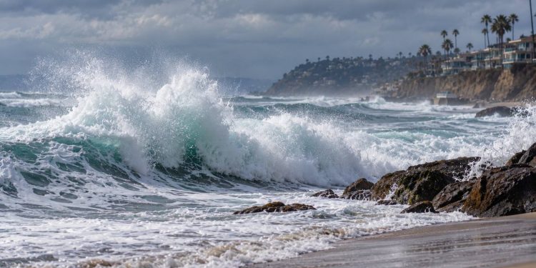 Large waves breaking along a Southern California beach under cloudy skies, illustrating powerful swells from Hurricanes Polo and Odalys.