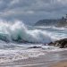 Large waves breaking along a Southern California beach under cloudy skies, illustrating powerful swells from Hurricanes Polo and Odalys.